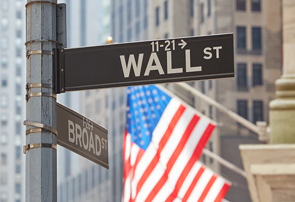 Wall Street road sign with flag behind it